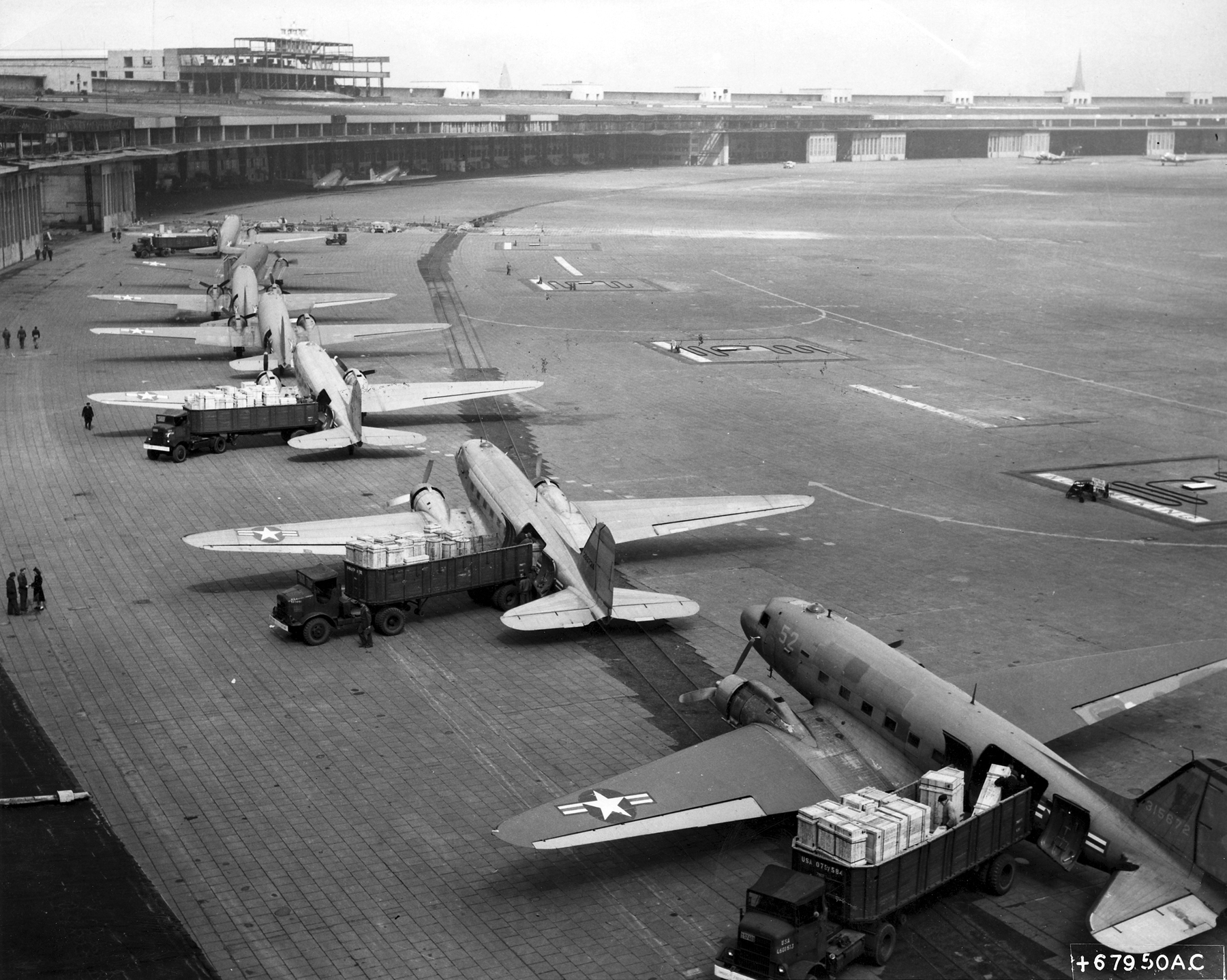 U.S. Air Force Douglas C-47 Skytrain transports unloading supples at Templehof Airport, Berlin, 1948. (U.S. Air Force)