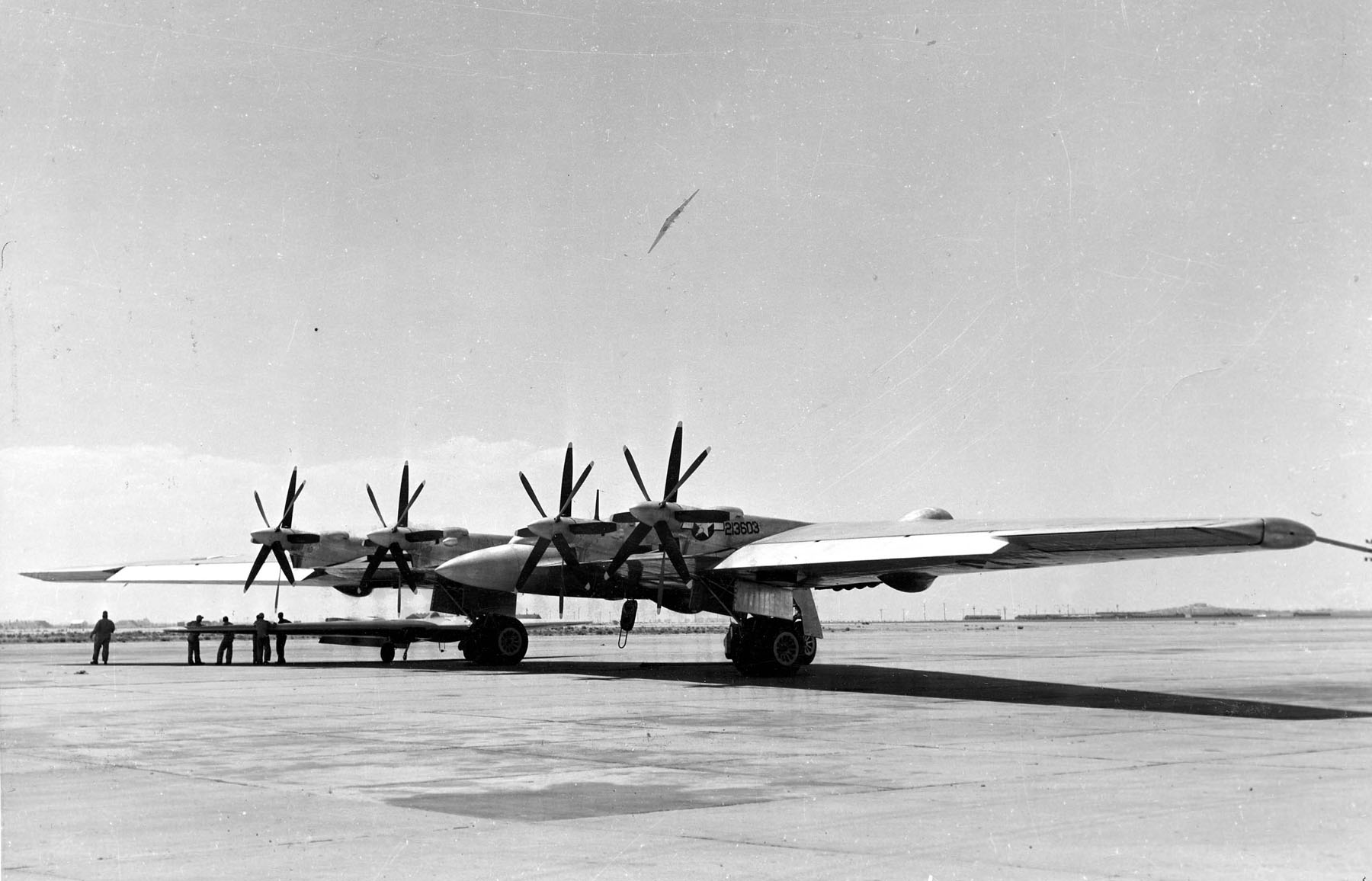 This view of the Northrop XB-35 Flying W 42-13603 on the ramp at Muroc Air Force Base shows the pusher arrangement of four-bladed contra-rotating propellers. In the background, a turbojet-powered YB-49 is in a right bank.. (U,S. Air Force)