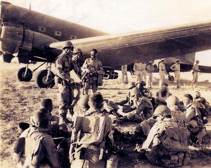 Coloenel James M. Gavin, United States Army, commanding officer, 505th Parachute Infantry Regimeent, with his men before Operation Husky, 9 July 1943. (U.S. Army)