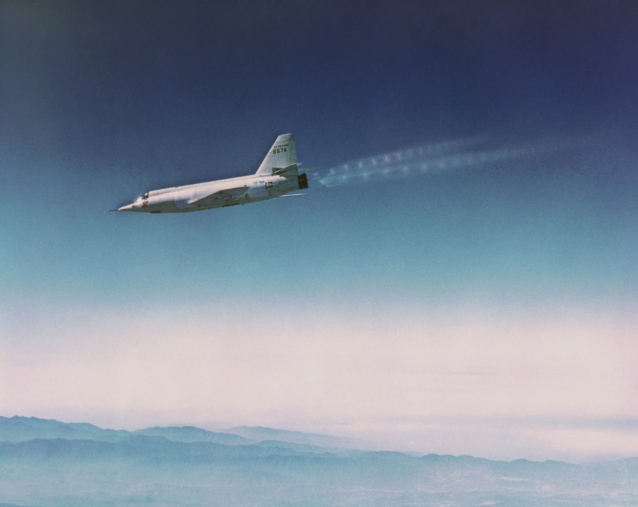 Bell X-2 46-674 in flight over Southern California, 1955–56. Note the supersonic diamond-shaped shock waves in the rocket engine's exhaust. (Bell aircraft Corporation)