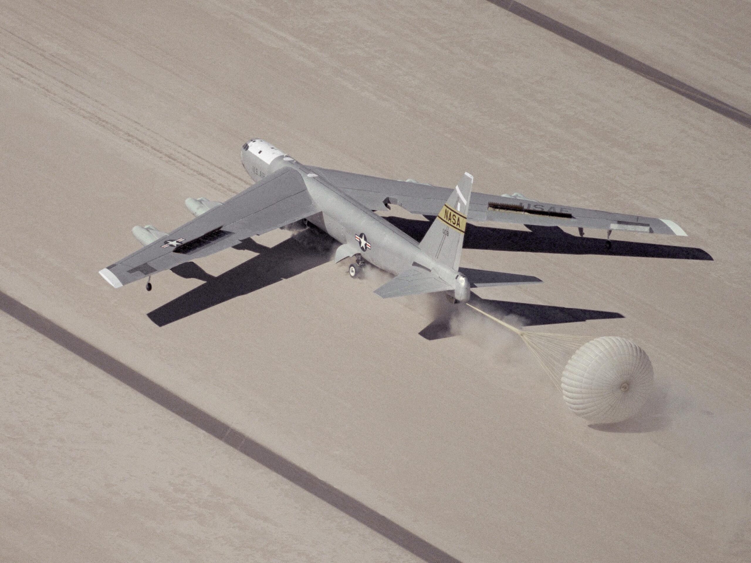 Balls 8 lands on a runway marked on Rogers Dry Lake at Edwards Air Force Base, California. The drogue parachute helps to slow the airplane. (NASA)