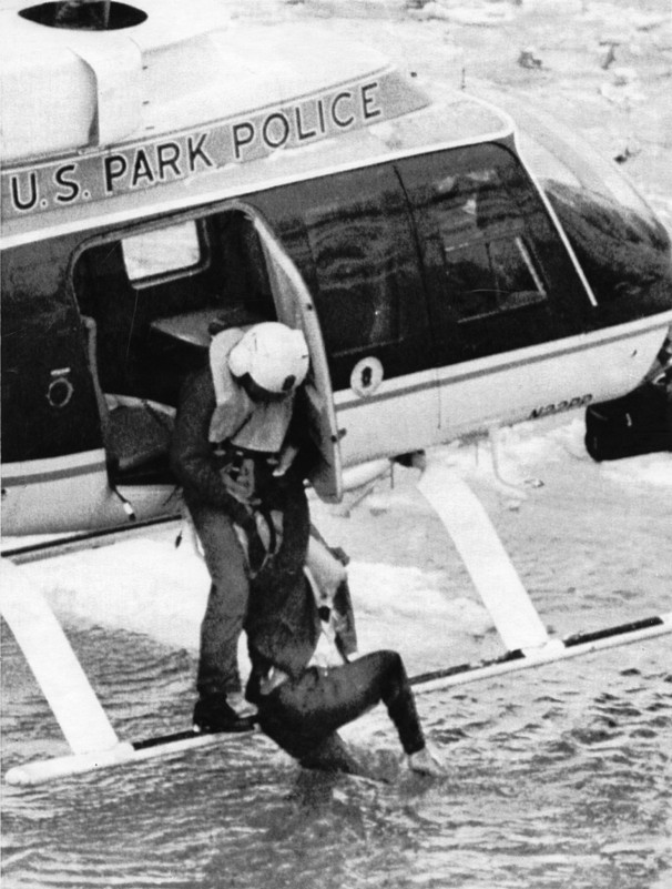 Officer M.E. Windsor stands on the skids of the Bell 206L-1 and holds on to a survivor of Flight 90, 13 January 1982. (UPI)
