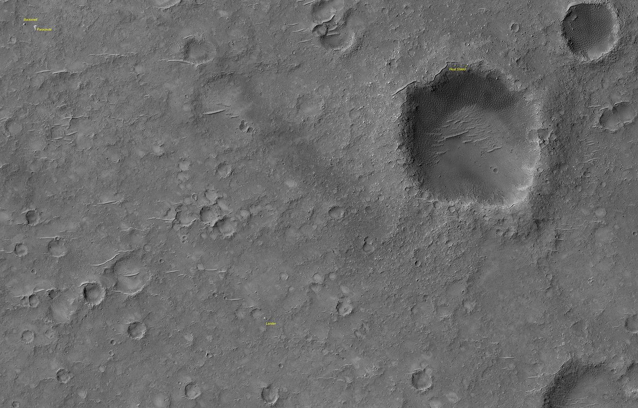 Mars rover Spirit landing site. The lander is at the low center of the image. at upper left are the backshell and parachute. The lander's heat shield is at the upper right on the rim of the crater. This image was taken in December 2006. (NASA)