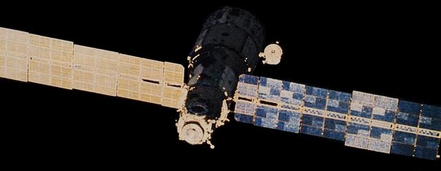 The Mir space station core module (DOS-7) in Earth orbit with solar panel array extended.