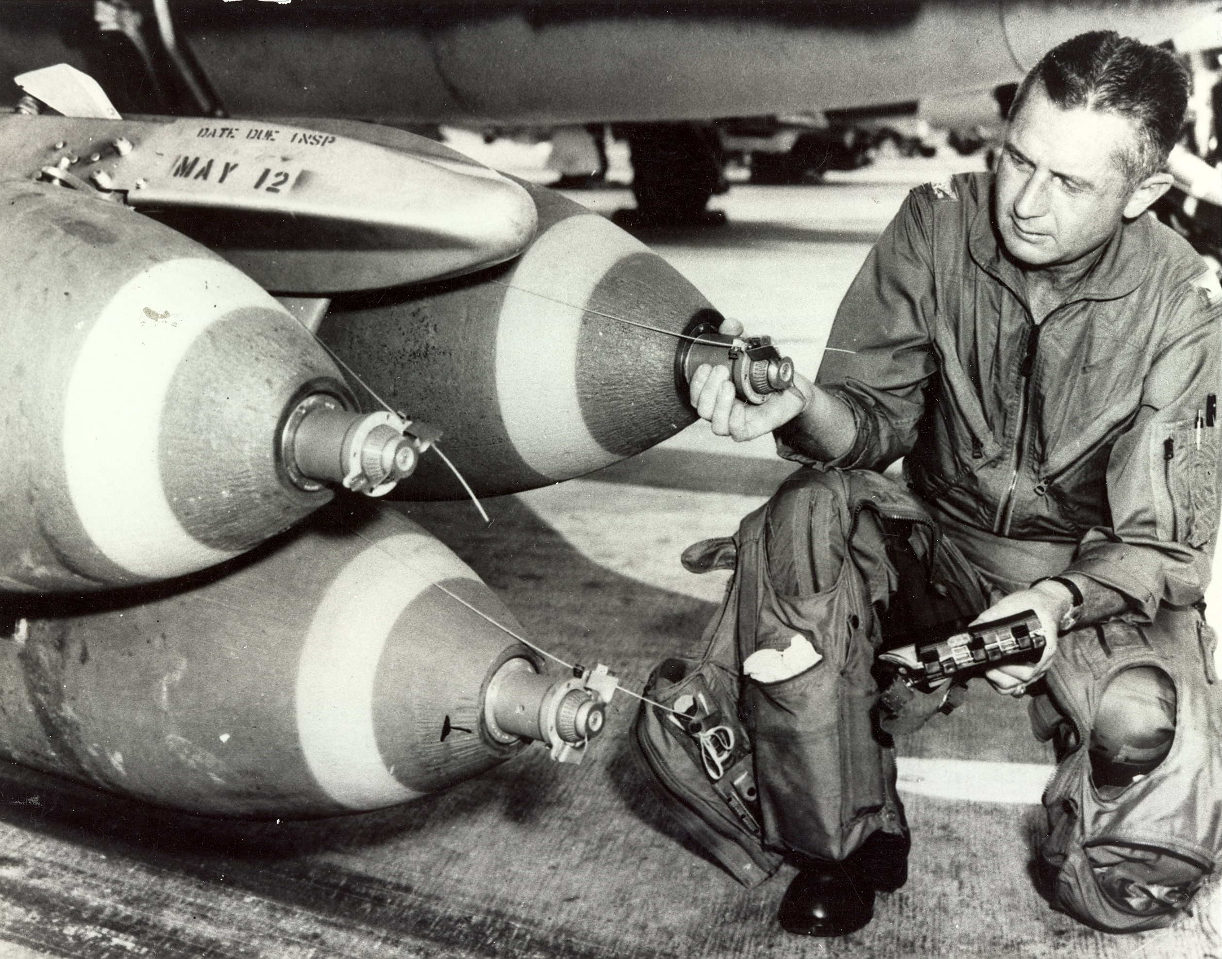 Colonel Robert R. Scott, commander, 355th Tactical Fighter Wing, checks the bombs loaded on a multiple ejector rack while preflighting his Republic F-105 Thunderchief. (U.S. Air Force)