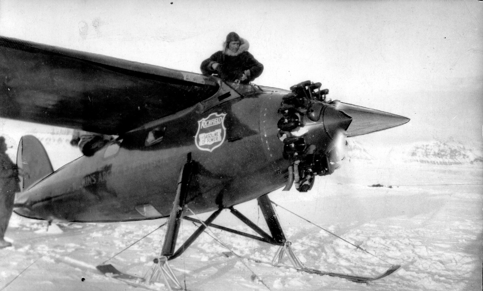Ben Eielson stands in the cockpit of the Lockheed Vega. The Wright Whirlwind engine is running. Note that the wood skis have been installed.