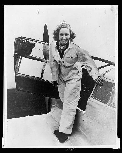 beryl Markham stands at The entrance to the cockpit of the Percival Vega Gull, probably late August 1936.