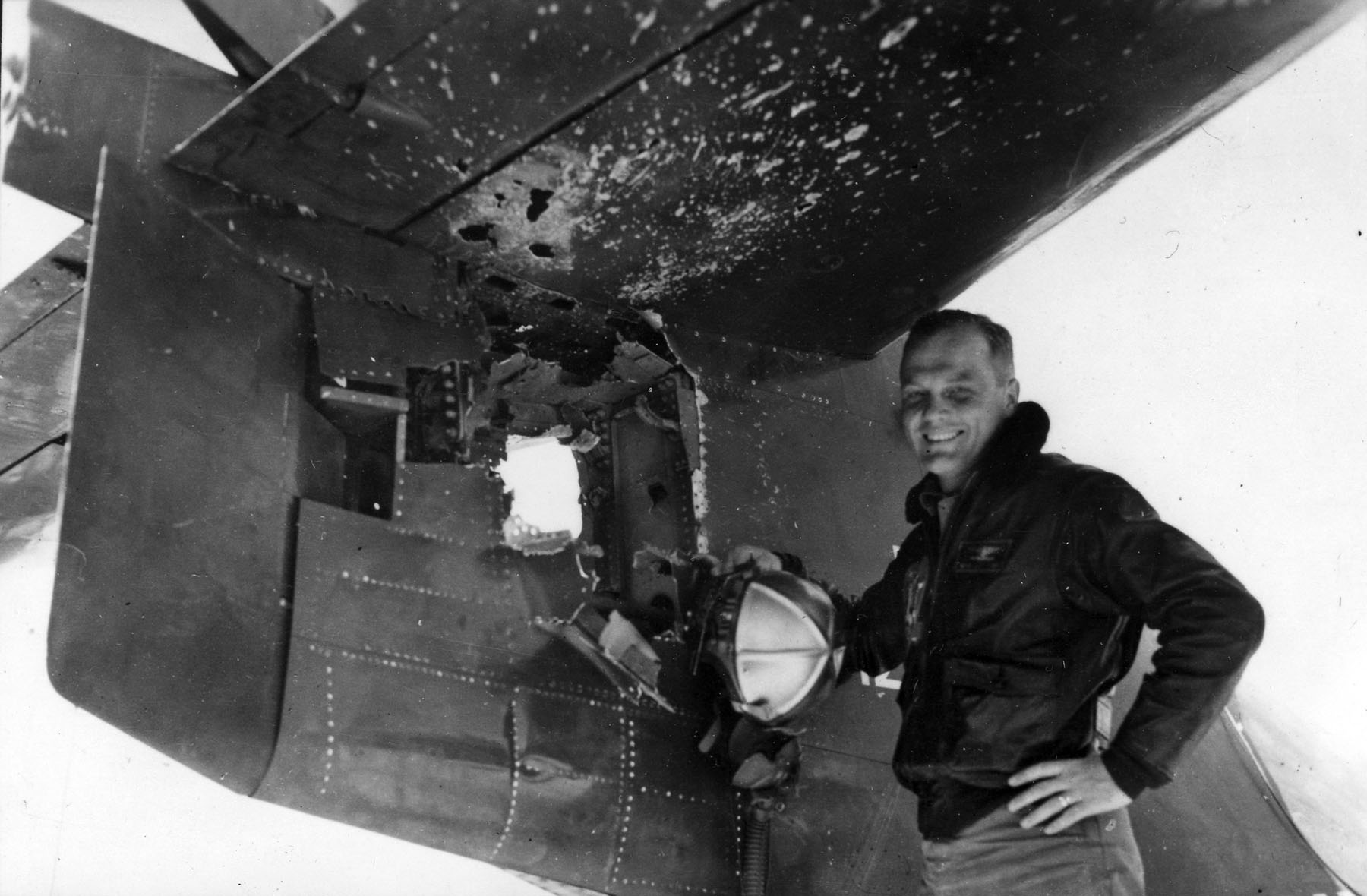 The combat survivability of Grumman's fighters earne dteh factory the nickname of "The Grumman Iron Works". In this photograph, future NASA astronaut John H. Glenn, the first American to orbit the Earth, examines some of the 714 holes in his F9F Panther. (U.S. Navy)