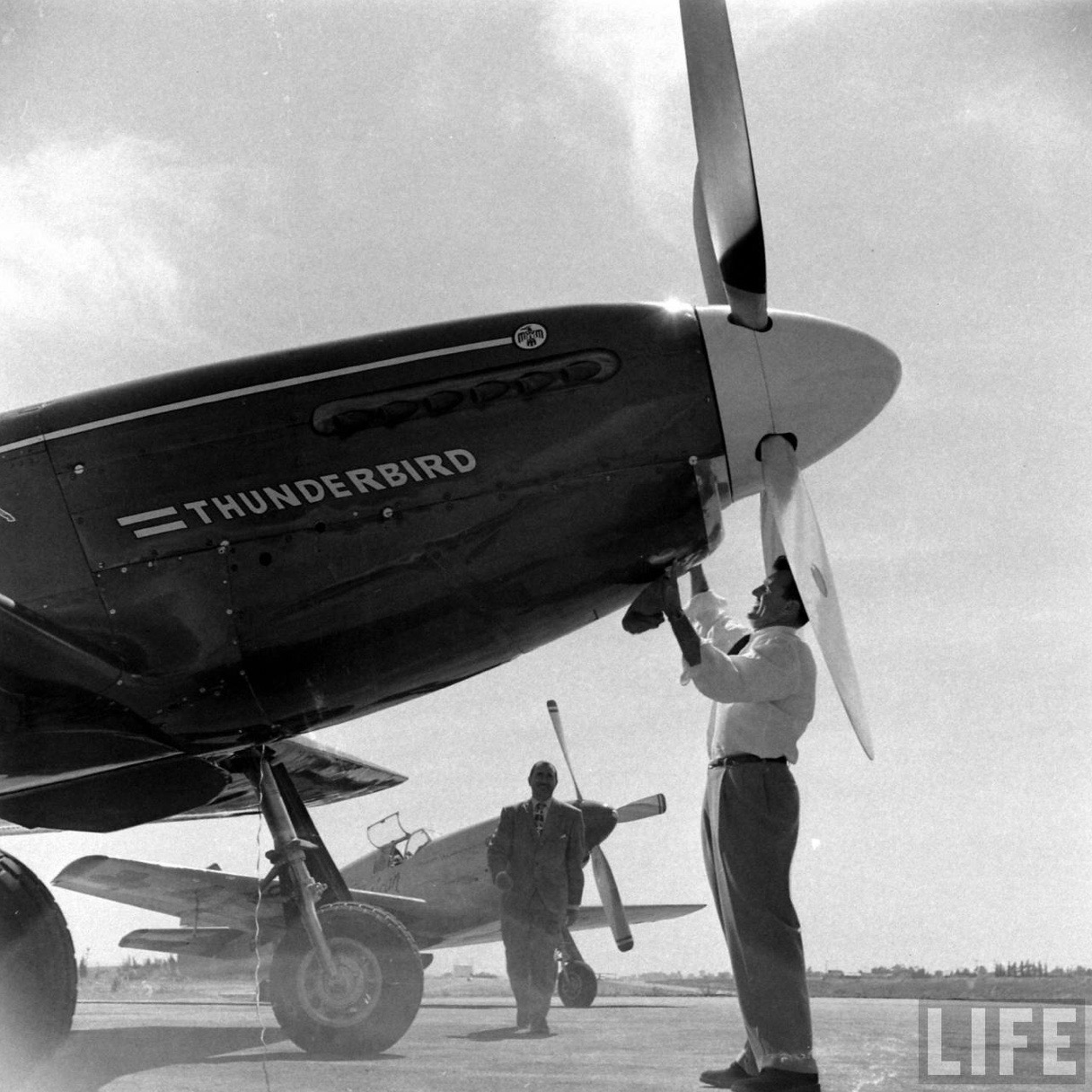 Joe De Bona polishes North American P-51C Mustang N5528N, “Thunderbird,” with Paul Mantz approaching, April 1949. Mantz’s P-51C NX1204, “Latin American,” is in the background. (Allan Grant/LIFE Magazine)