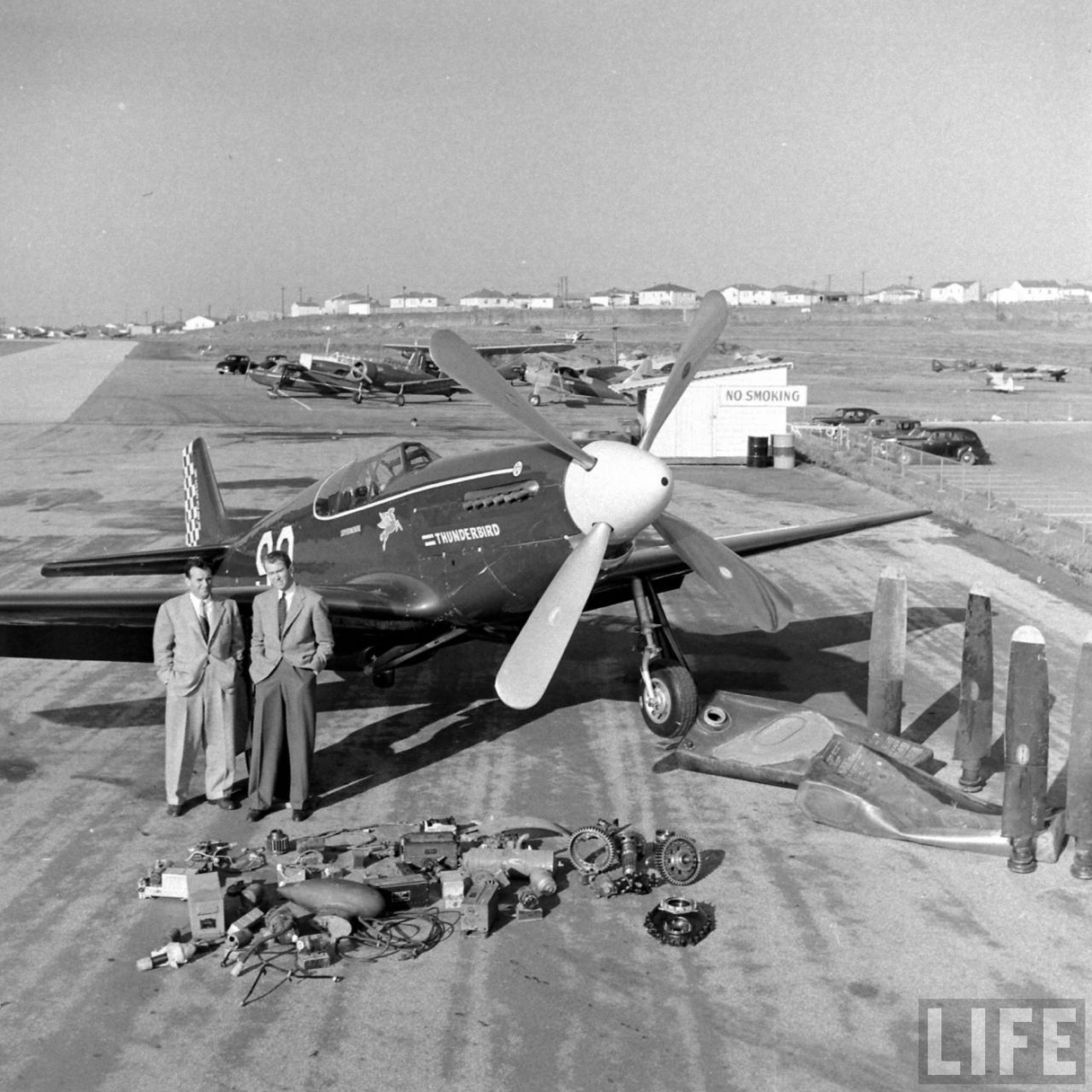Joe De Bona and Jimmy Stewart with Thunderbird, their P-51C Mustang racer, April 1949. Placed on the ramp in front of the airplane is equipment that has been removed or replaced. Note the four "cuffed" Hamilton Standard propeller blades along the right side of the photograph. They have been replaced with un-cuffed and polished Hamilton Standard blades. (Allan Grant/LIFE Magazine)