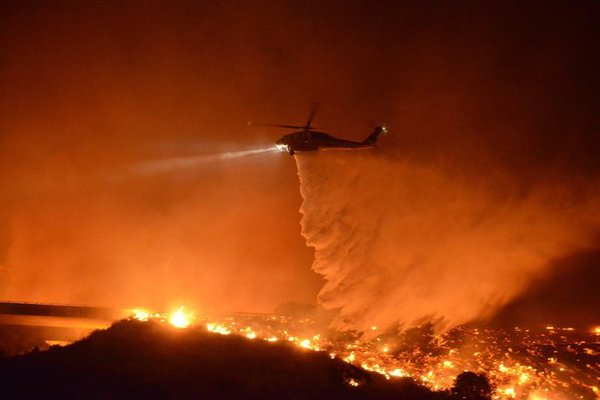 Copter 16, a Sikorsky S-70 Fire Hawk operated by the Los Angeles County Fire Department, makes a water drop on the Solimar Fire, early on the morning 26 December 2015. (Cal Fire)
