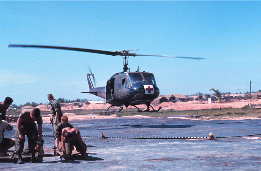 A Bell UH-1H medevac helicopter returns to its base, while ground personnel standby to offload the injured. (U.S. Army)