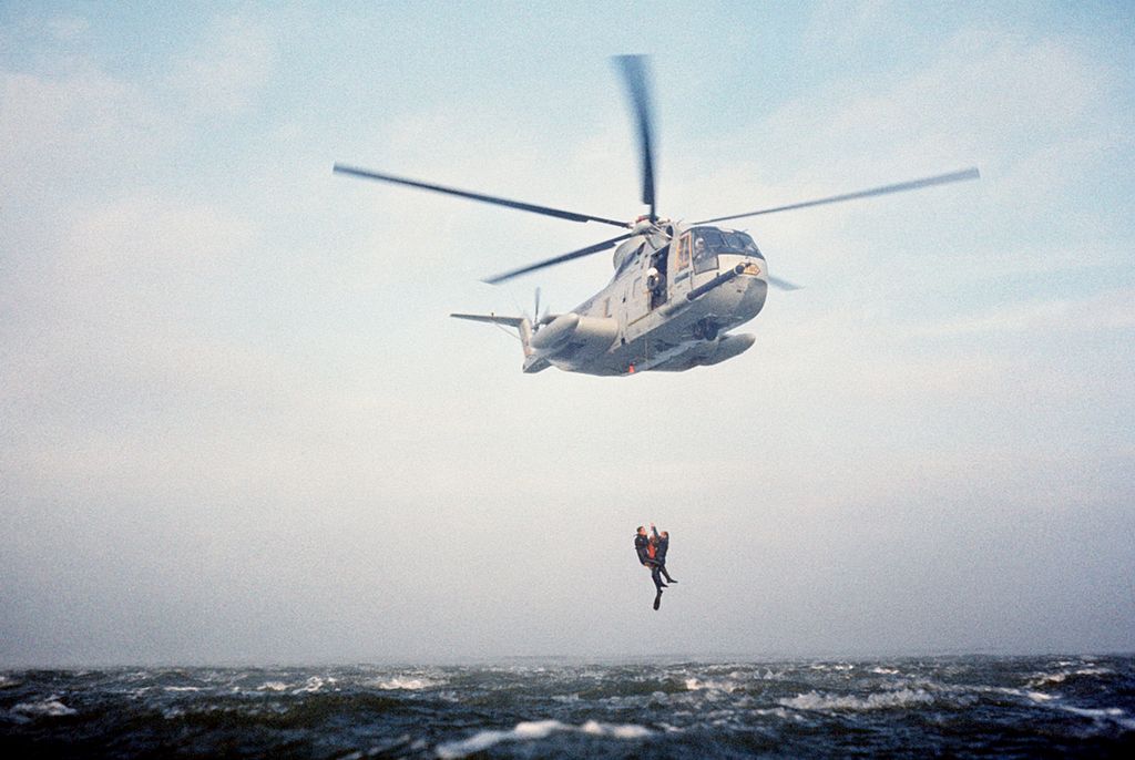 An HH-3E of the 129th Aerospace Rescue and Recovery Group, California Air National Guard hoists two PJs from the Pacific Ocean, 13 April 1977. (TSgt. Richard M. Diaz, U.S. Air Force)