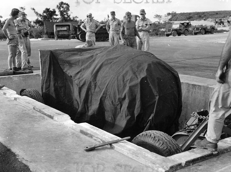 The Mark III implosion bomb and its trailer are lowered into the pit in preparation for loading aboard Bockscar, 8 August 1945. (U.S. Air Force)