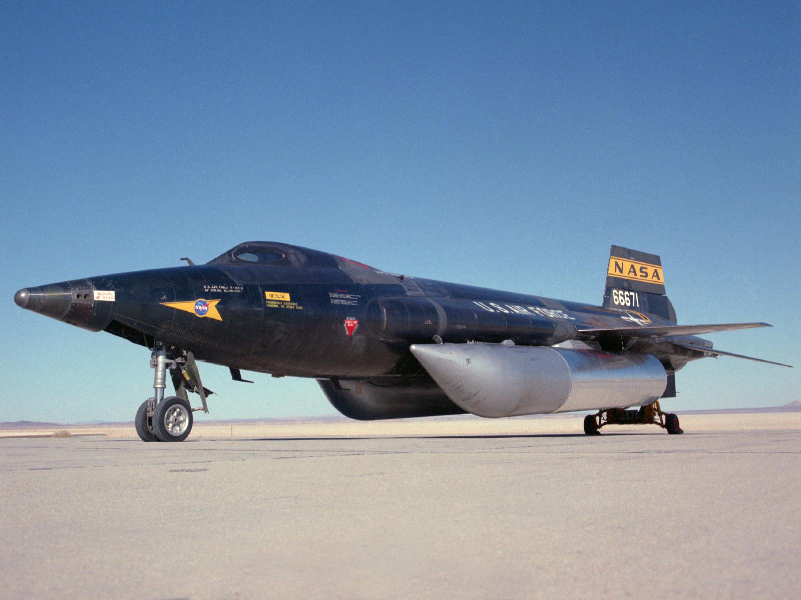 North American Aviation X-15A-2 56-6671 on Rogers Dry Lake. In addition to the lengthened fuselage and external tanks, the nose wheel strut is longer and the windshields have been changed to an oval shape. A wheeled dolly supports the aft end of the rocketplane. (NASA)