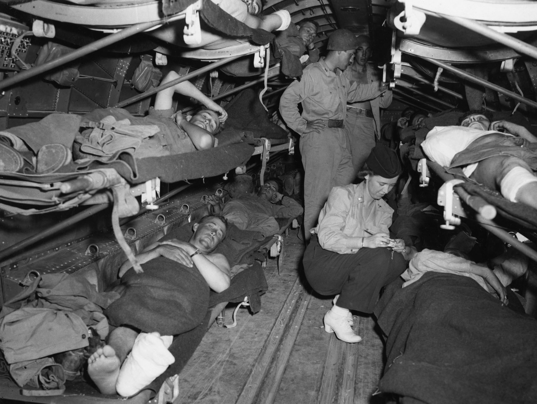 A Flight Nurse, Lieutenant Katye Swope, USAAF, checks the name of a patient aboard a transport enroute from Sicily to North Africa, July 1943. (U.S. Air Force)