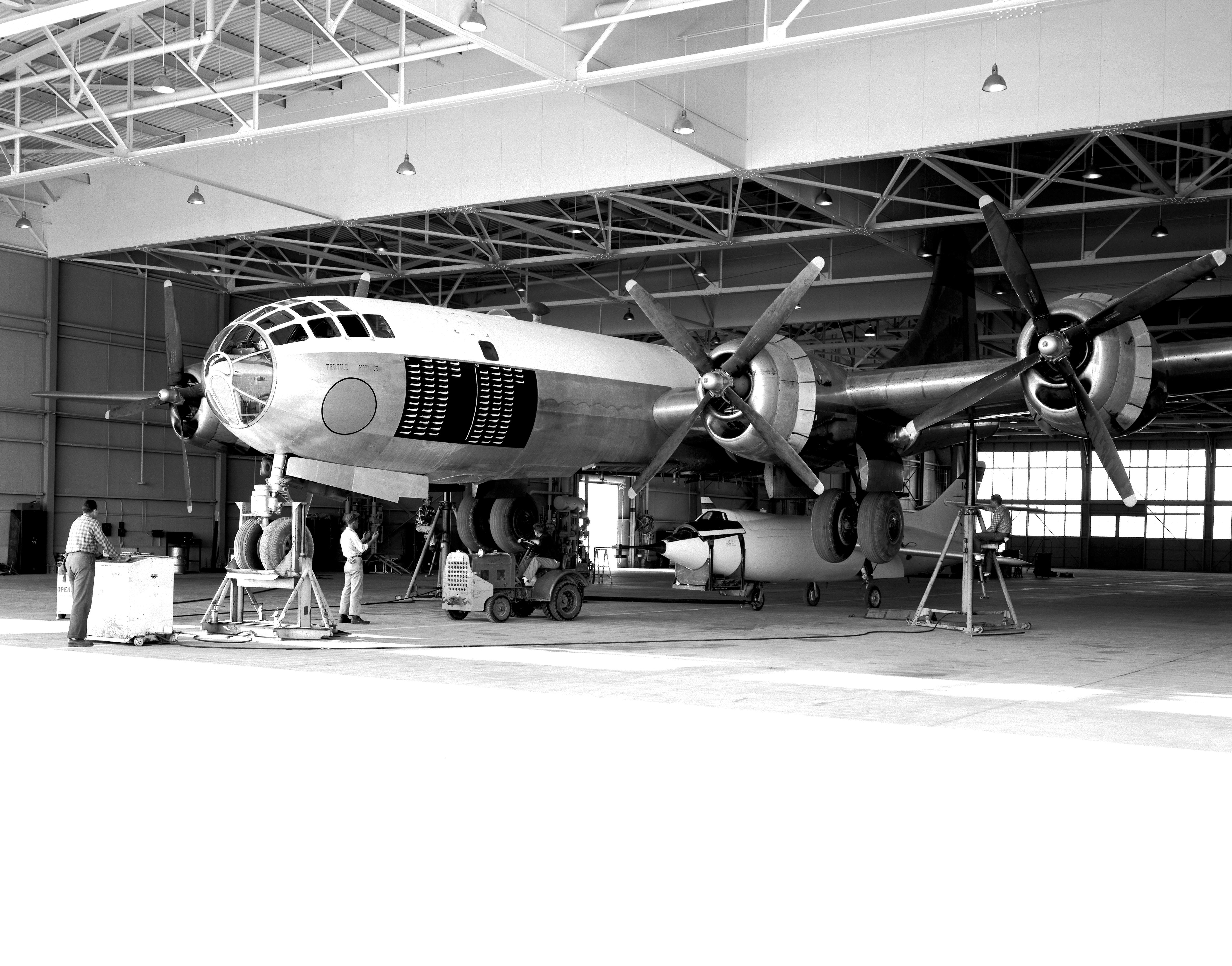 The P2B1-S is jacked up inside a hangar at Edwards AFB so the the Douglas D-558-II Skyrocket can be loaded aboard.