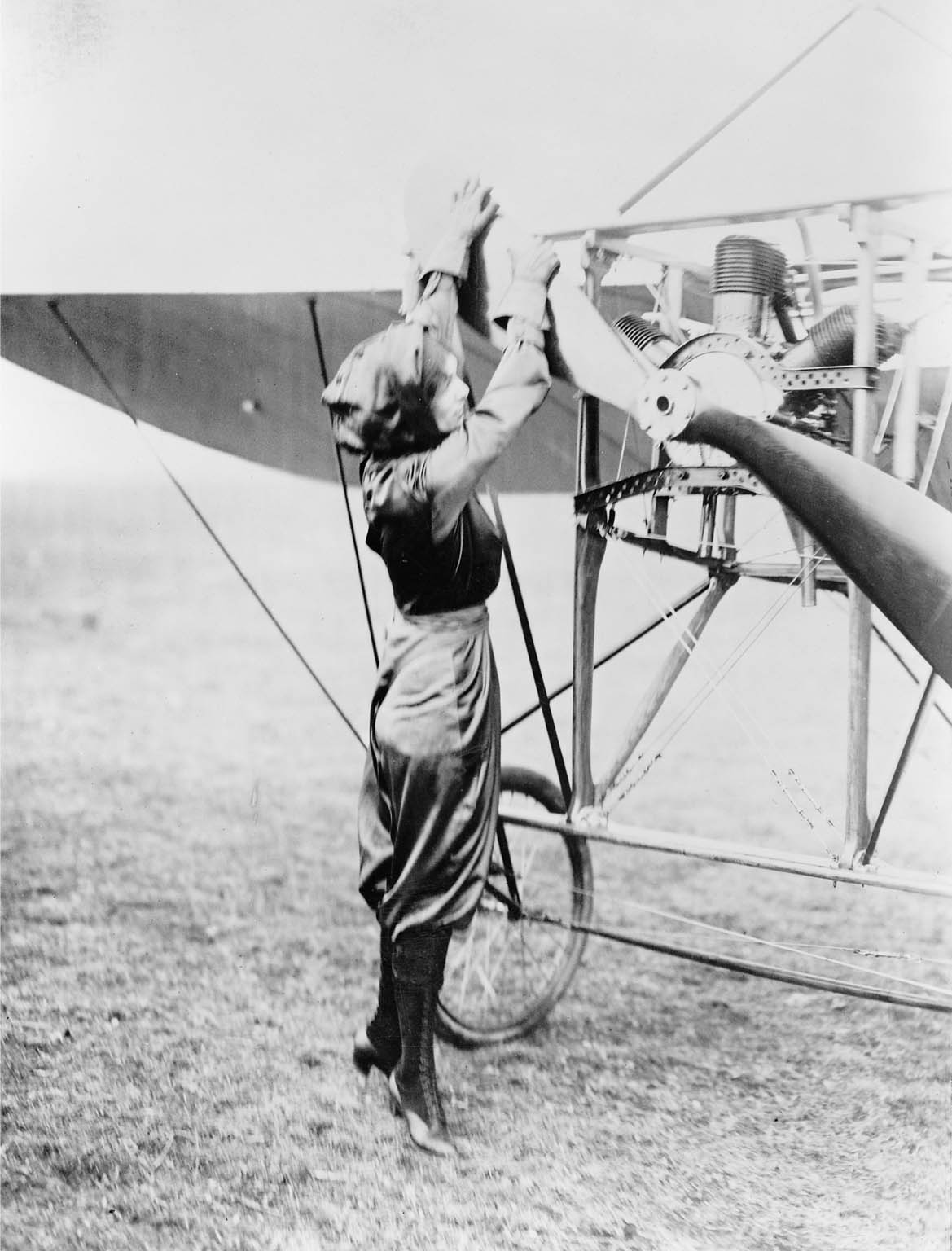 Harriet Quimby, wearing her purple satin flying suit, pulls the Chauvière Intégrale propeller of the Blériot XI to start the air-cooled Anzani 72° W3 ("fan" or "semi-radial") 3-cylinder engine.