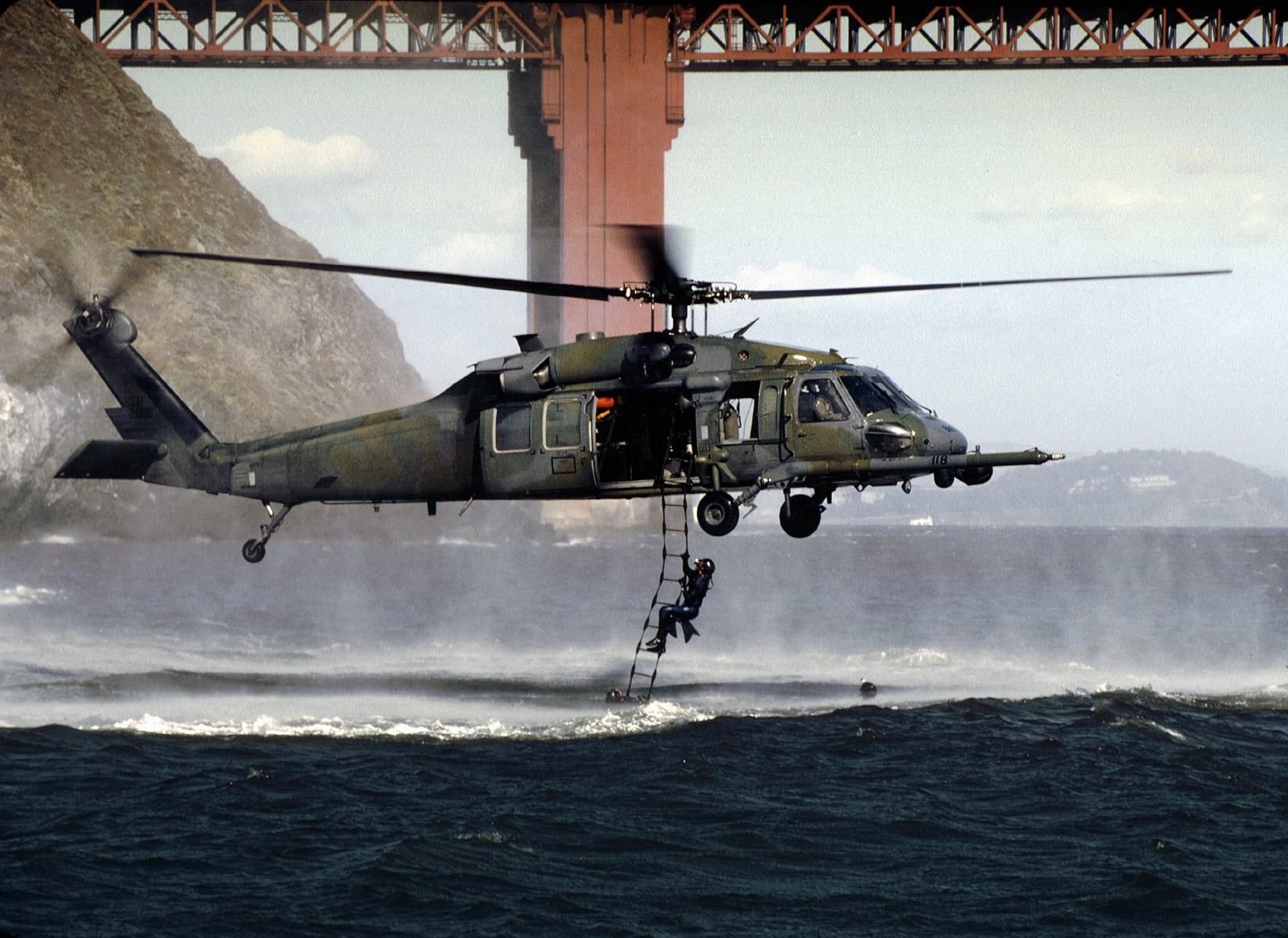 Sikorsky HH-60G Pave Hawk 88-26118 of the 12th Rescue Wing—a sister ship of Jolly 110—recovers pararescue jumpers during a training mission outside of San Francisco's Golden Gate. (TSGT Lance Cheung, U.S. Air Force) 