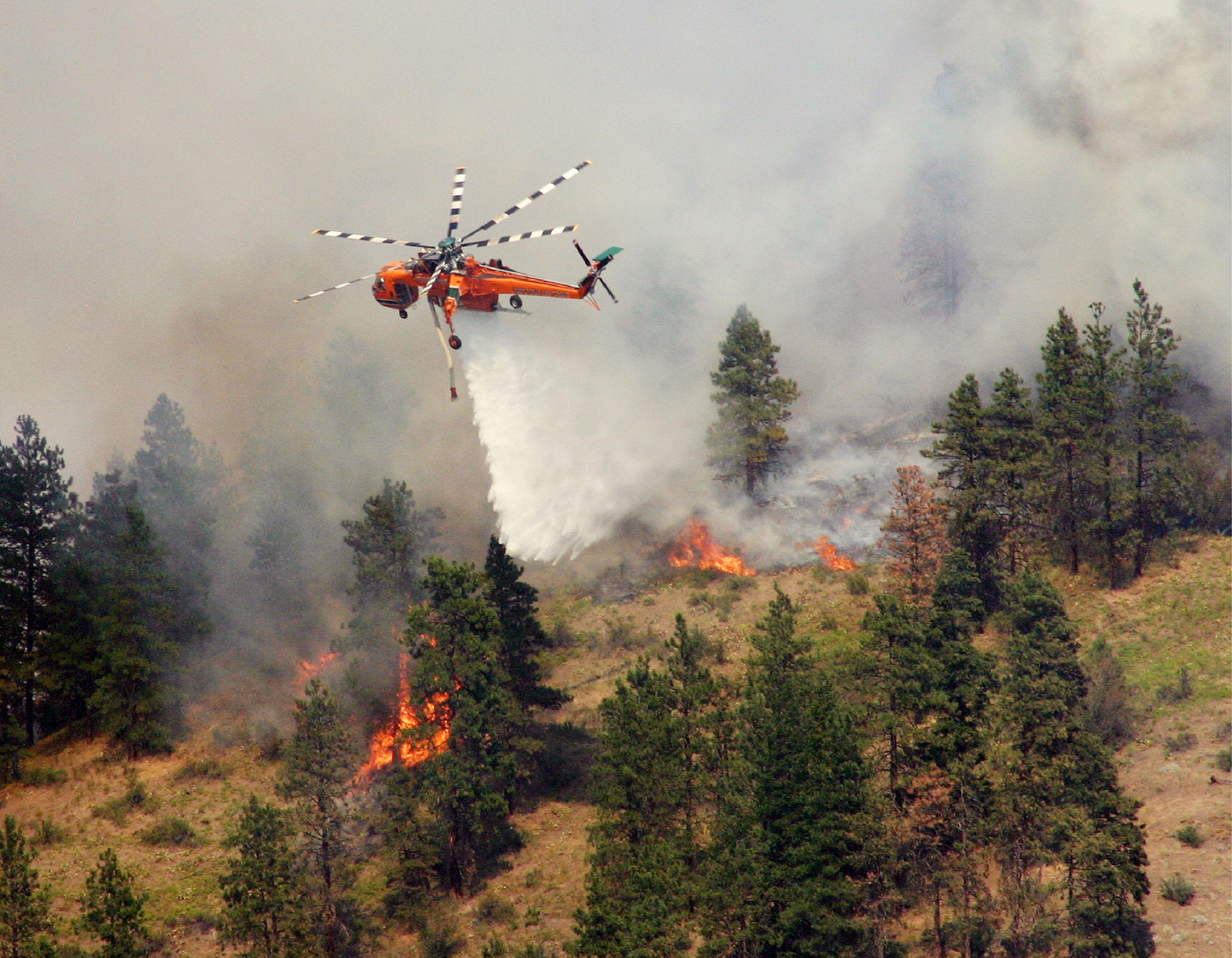An Erickson Air-Crane, Inc. Sikorsky S-64 Skycrane drops water on a forest fire. (Sikorsky Archives)