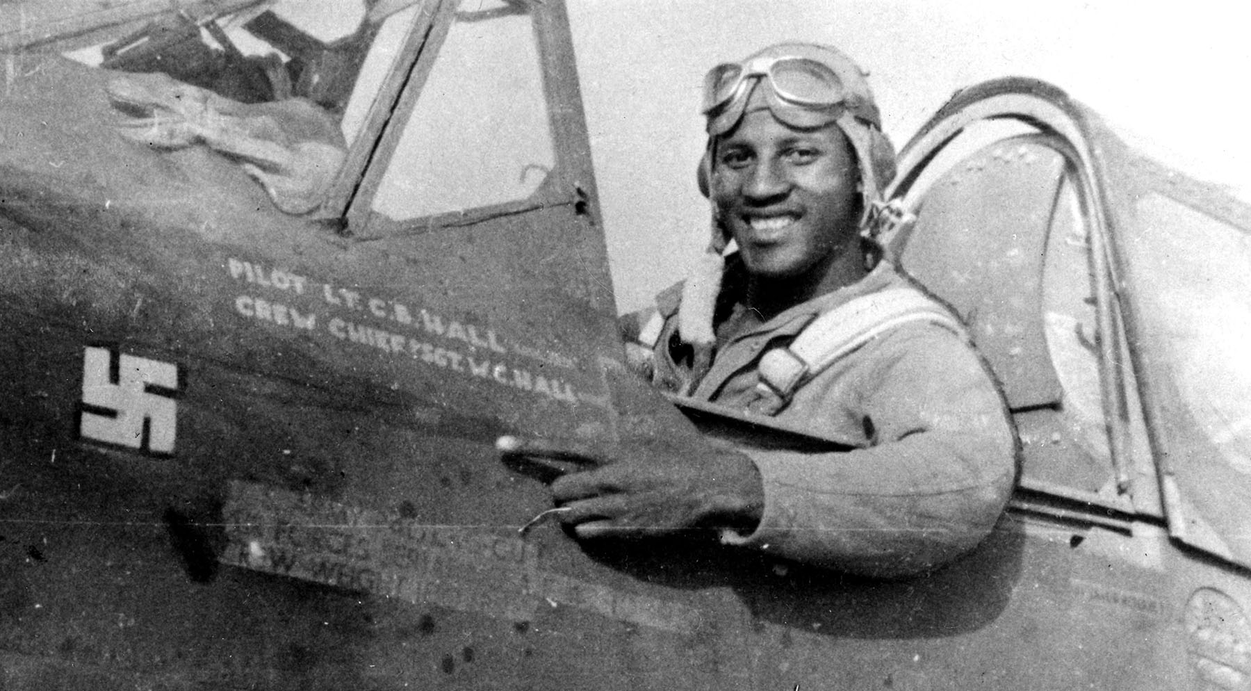 1st Lieutenant Charles B. Hall, in the cockpit of his Curtiss P-40L Warhawk fighter, points to a swastika which represents the Luftwaffe Focke-Wulf Fw 190 that he shot down, 2 July 1943. (U.S. Air Force)