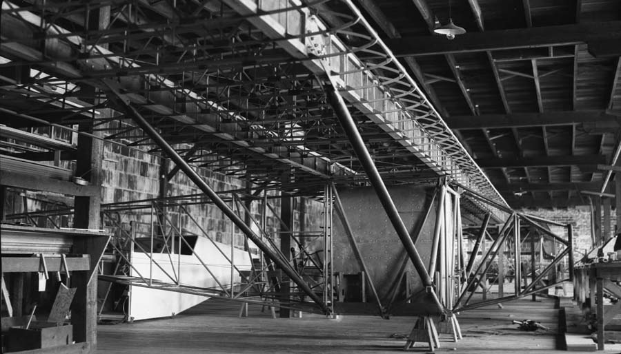 This photograph shows the wooden structure of the wing and welded tubular framework of the fuselage of Spirit of St. Louis. The forward fuselage fuel tank is in place. (Donald A. Hall)