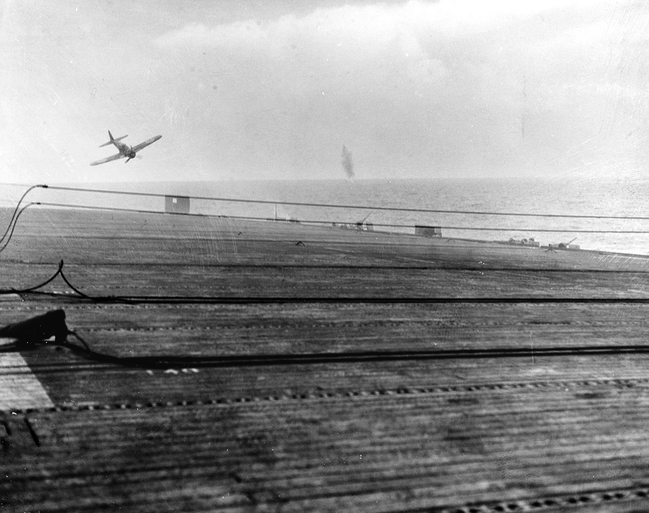"A Japanese kamikaze pilot in a Mitsubishi A6M5 Model 52 ("Zero") crash dives on the U.S. Navy escort carrier USS White Plains (CVE-66) on 25 October 1944. The aircraft missed the flight deck and impacted the water just off the port quarter of the ship." (Naval History and Heritage Command 80-G-288882)