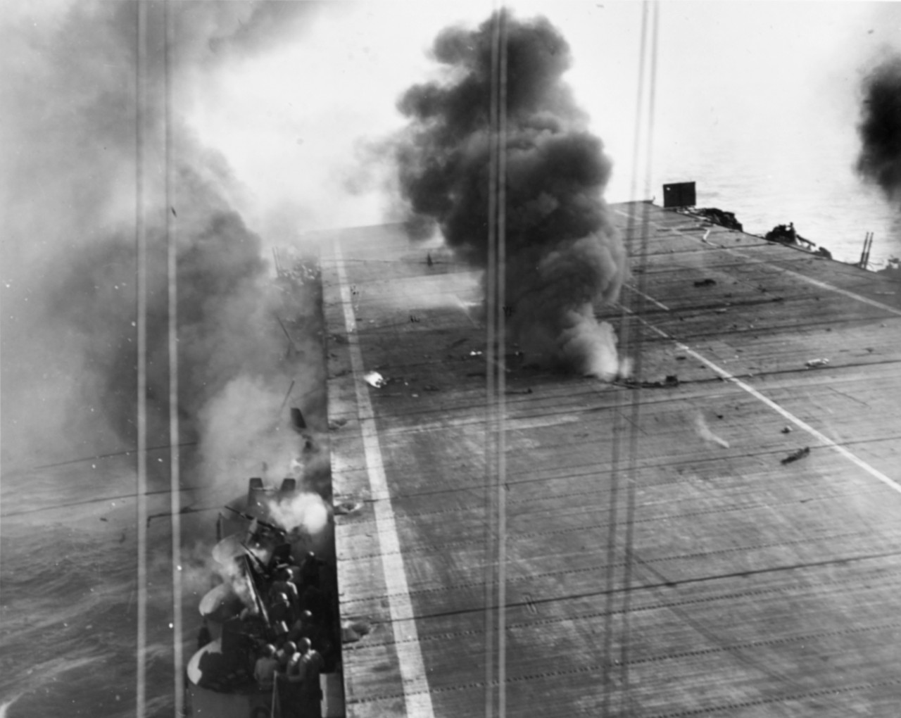 "Effect of a crash dive on Suwanee flight deck. 250 kilogram bomb has just exploded between flight an dhangar decks and fire billows out, 25 October 1944. (Naval History and Heritage Command NH 71528)